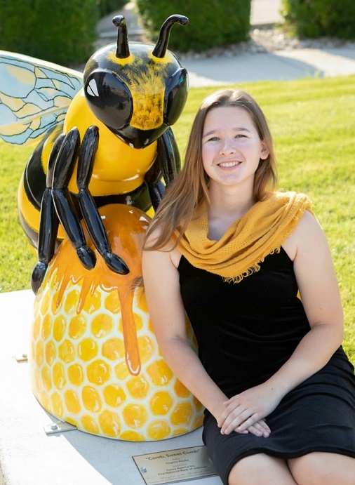 Blonde female next to bee sculpture
